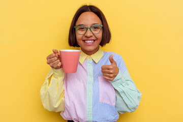 Young student mixed race woman holding a smug isolated on yellow background