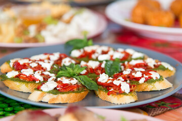 Mini canapes with green avocado paste, tomato, red pepper, cream sauce and bread. Decor with basil and sesame seeds. A light snack for your appetite.