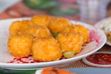 Breaded chicken nuggets, ready to eat on a plate. On a table with a bright background.