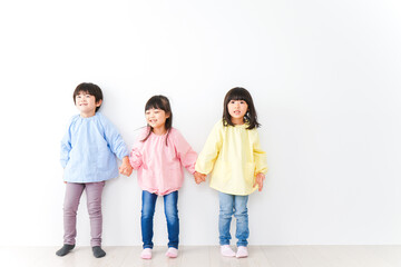 Obraz premium 壁に並ぶ3人の幼稚園児