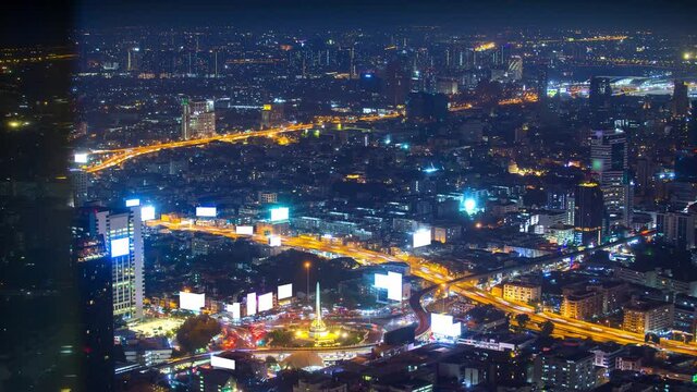 time lapse aerial view of Victory monument, famous landmark center of Bangkok city, Thailand, at night and heavy traffic jam transportation at roundabout and on highway, motorway, tollway 