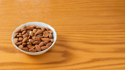 Almonds in white porcelain bowl copy space