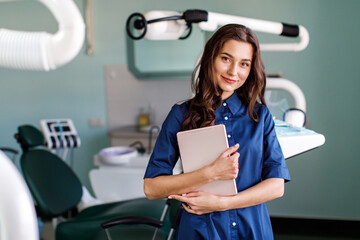Young doctor in a dental clinic. Portrait of young female doctor dentist with digital tablet in...
