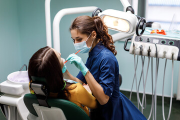 The beautiful young woman is at the dentist. She sits in the dentist's chair and the dentist...