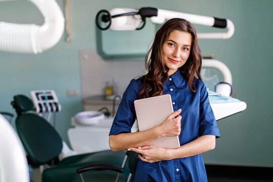Young doctor in a dental clinic. Portrait of young female doctor dentist with digital tablet in dental office - Powered by Adobe