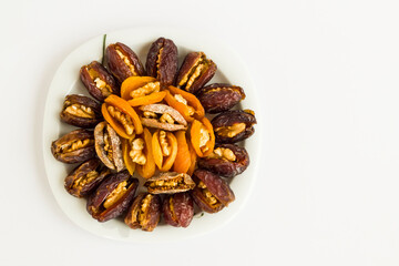 A plate of Ramadan-Iftar foods;dry date fruits,apricot and walnuts in.White background with copy space