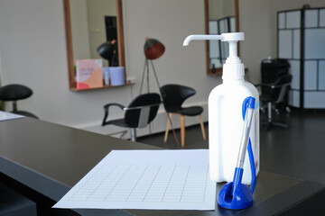 Hairdresser reception with hand sanitizer, pen and questionnaire to collect personal information from customers.