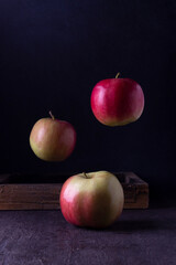Apples on the boom of a wooden box. Levitation. Dark photo.