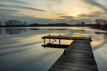 Obraz premium A wooden footbridge on the lake and beautiful evening clouds, Stankow, Lubelskie, Poland