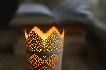 Open book and lit candle on a table. Selective focus.