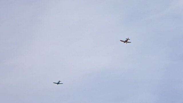 Two light aircrafts with one propeller flying in the blue summer sky