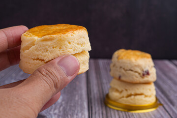 Hand holding of scone traditional English delicious freshly baked homemade with vintage wall background. Close-up photo. Dessert and relaxation concept