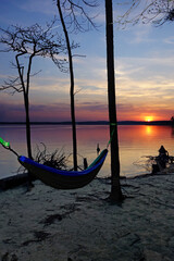 A hammock hanging in the trees at sunset on the shore of Jordan Lake State Park campground in North Carolina