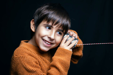 Smiling child plays pretend talking on the phone with a can
Conceptual of lifestyle, home life