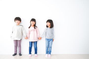 Fototapeta premium 壁に並ぶ3人の子どもたち
