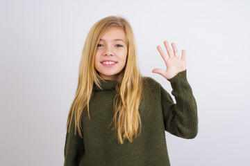 Caucasian kid girl wearing green knitted sweater against white wall showing and pointing up with fingers number five while smiling confident and happy.