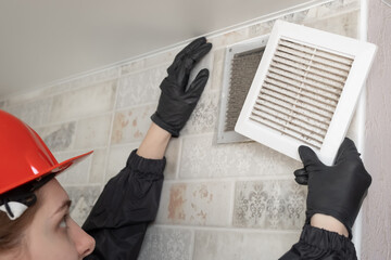 A professional worker in a protective suit and helmet cleans the Ventilation grill. Flat Panel...