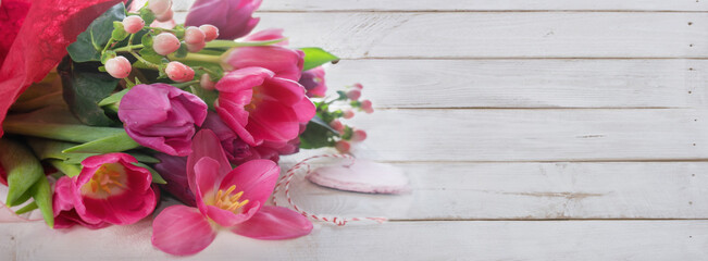 Bunch purple tulips on white vintage planks. Horizontal mother day background with a heart and space for text.