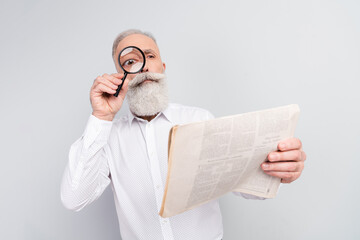 Photo of curious interested old man look magnifier eye newspaper article isolated on grey color...