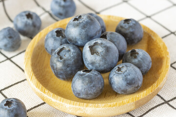 Blueberries in a wooden plate on a checkered towel