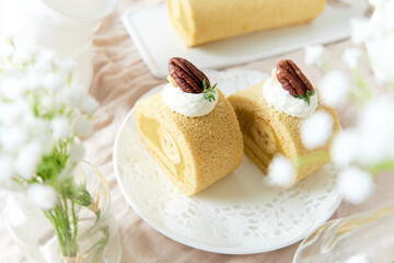 Banana Swiss Roll Cake with banana cream filling set on white cafe table.