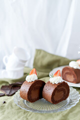 Chocolate Swiss Roll Cake with Chocolate cream filling and Strawberry set on cafe table.
