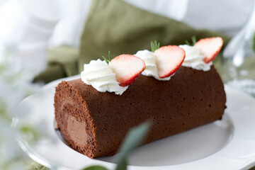 Chocolate Swiss Roll Cake with Chocolate cream filling and Strawberry set on cafe table.