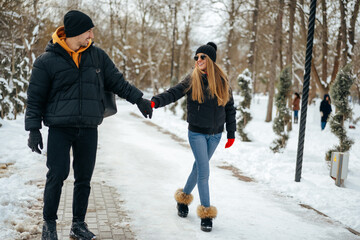 Fototapeta na wymiar Young happy couple in love having a walk in a winter park