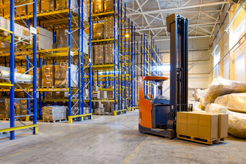 Interior of a modern warehouse storage with rows and goods boxes on high shelves. Pallet truck...