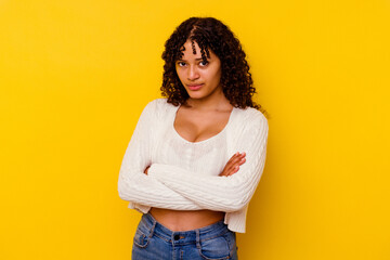 Young mixed race woman isolated on yellow background frowning face in displeasure, keeps arms...