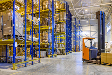 Interior of a modern warehouse storage with rows and goods boxes on high shelves. Pallet truck parking near shelves
