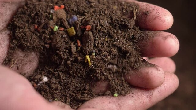 microplastics in soil. plastic waste in agricultural field. soil pollution, agriculture, tiny plastic particles are polluting soil and water, plastic in human hands