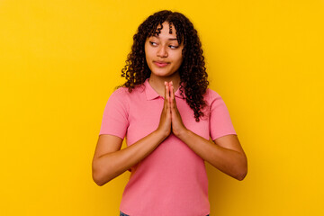 Young mixed race woman isolated on yellow background praying, showing devotion, religious person...