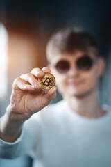 closeup of male investor holding golden bitcoin or cryptocurrency in hand
