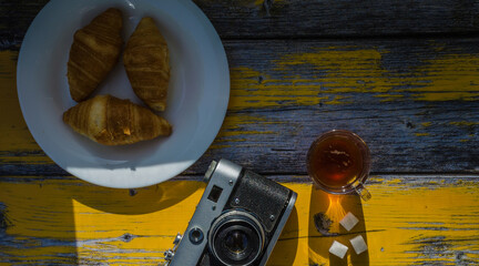 Still life with retro camera and cup of coffee on the wooden background. Sweets on the plate on the wooden background