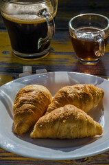 Still life with retro camera and cup of coffee on the wooden background. Sweets on the plate on the wooden background