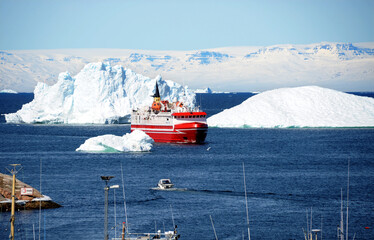 A red cruise ship arrives at the port of Ilulissat, Greenland. © minspa