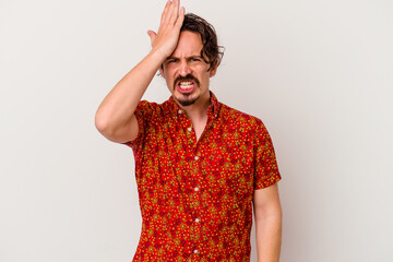 Young caucasian man isolated on white background forgetting something, slapping forehead with palm...