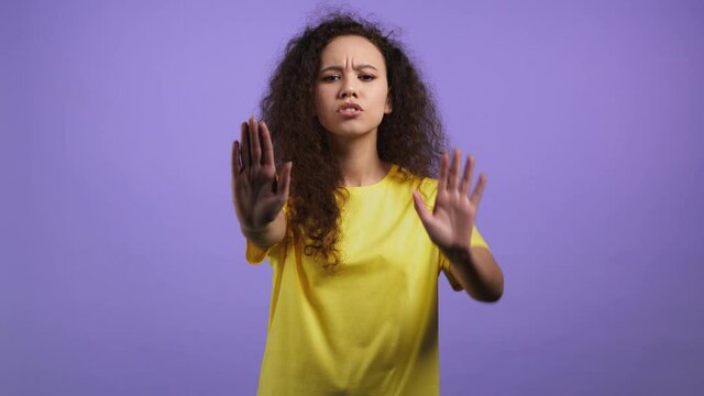 Pretty girl disapproving with no palms hands sign makes basta, negation, enough gesture. Denying, Rejecting, Disagree, Portrait of pretty girl on violet background