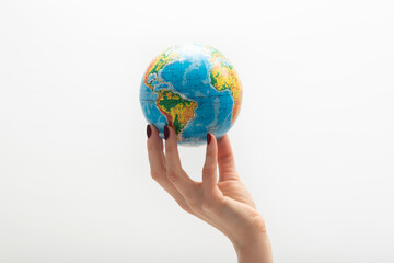 Globe at the tip of woman's fingers. Female hand holds globe. World in human hands. White background