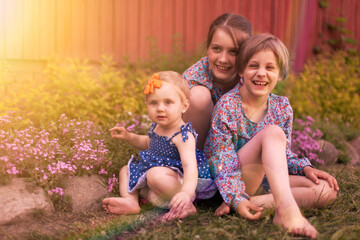 Three girls having fun on spring grass near country house