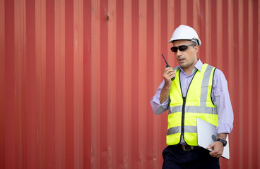 Man engineer using walkie-talkie in shipping yard, Industrial worker is controlling container...