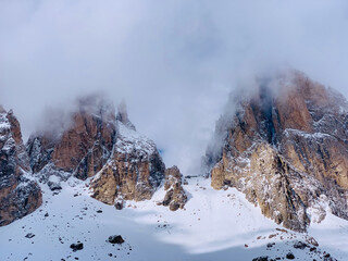 Fototapeta na wymiar Italian Dolomites peak with fresh snow, hidden partly by clouds.
