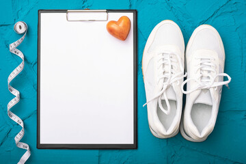 fitness at home - sheet of paper with pen and white sneakers