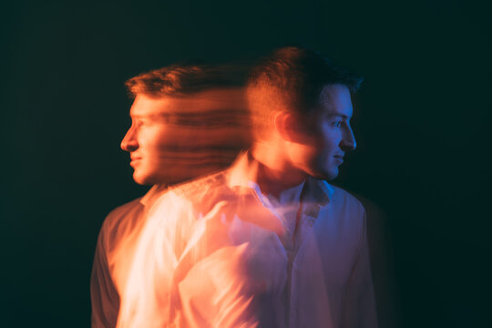 Split personality. Inner conflict. Mental stress. Bipolar disorder. Conceptual art portrait. Calm and depressed man in emotional reflection each other isolated green blur light double exposure.