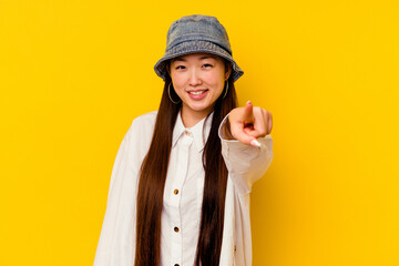 Young chinese woman isolated on yellow background pointing to front with fingers.