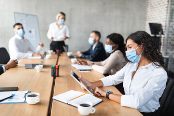 Businesswoman In Face Mask Using Tablet During Corporate Meeting Indoor