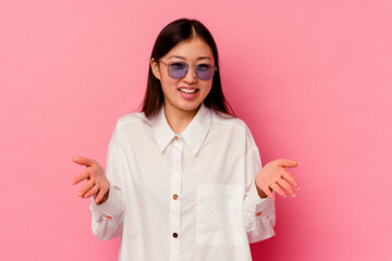 Young chinese woman isolated on pink background holding something with both hands, product presentation.