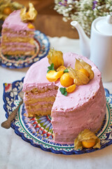 Pumpkin sponge cake with berry cream, decorated with physalis. Side view. 