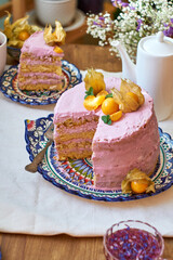 Pumpkin sponge cake with berry cream, decorated with physalis. Side view. 